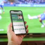 persona che segue i risultati live sul cellulare
